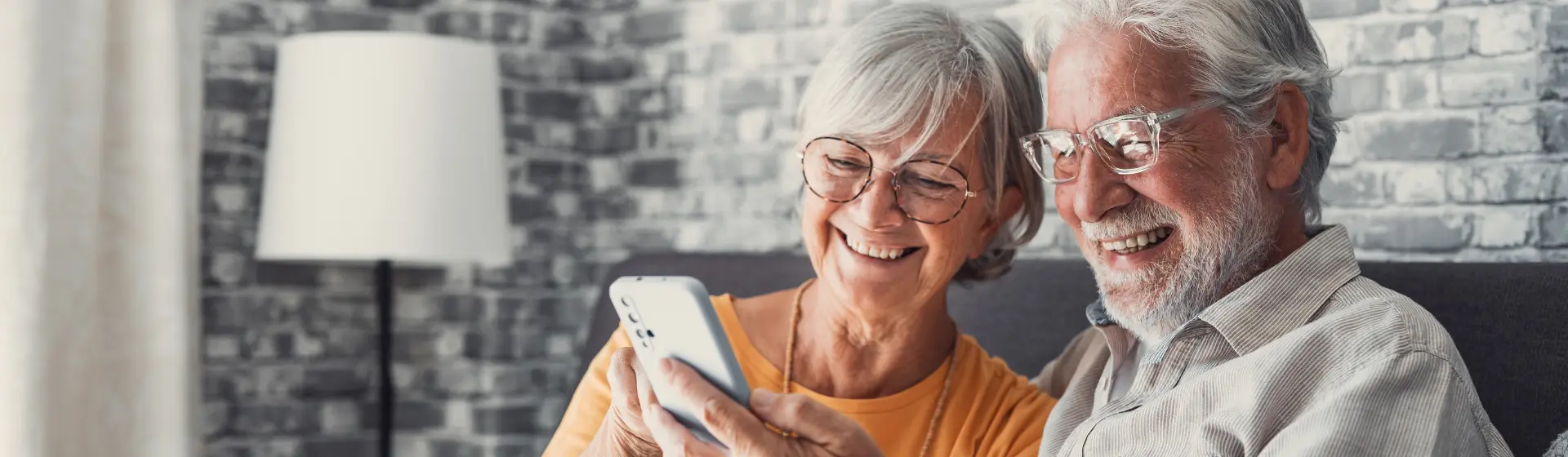 Caucasian senior couple with glasses smiling at phone