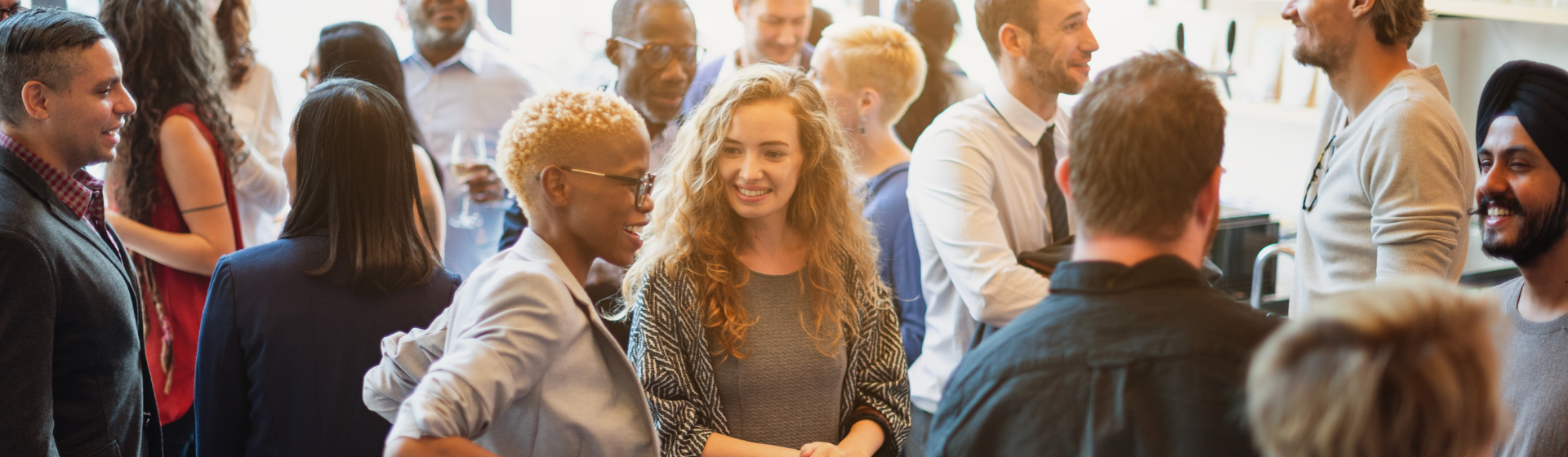 Men and women of various ethnicities engaged in conversation, enjoying a lively social event.
