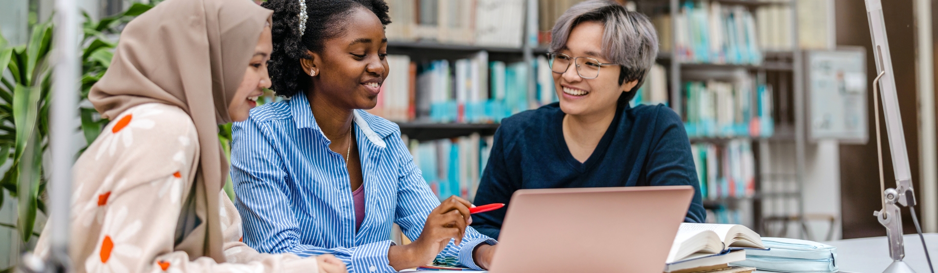 Multiethnic group of students sitting in a library and studying together